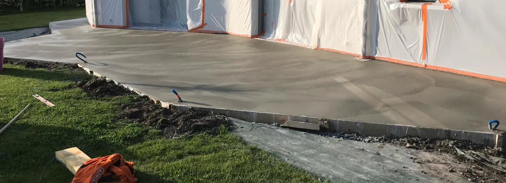 Dalle béton fraîchement coulée et lissée le long d'une maison, coffrage périphérique en place