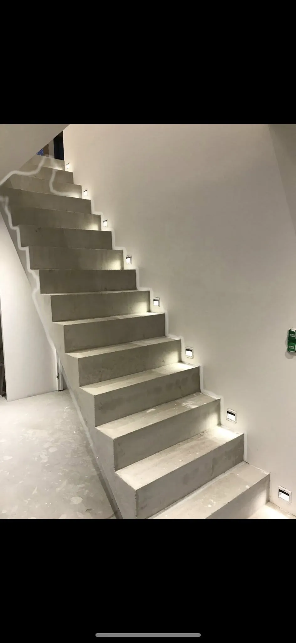 Escalier droit en béton coulé en place dans une maison, avec spots encastrés dans le mur